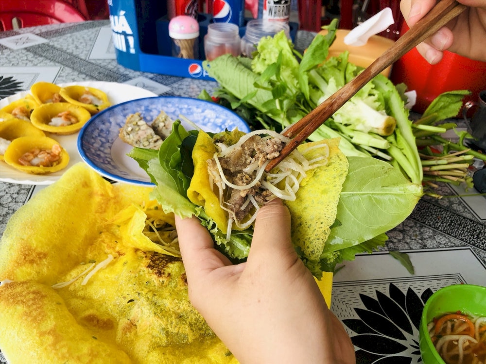 Banh khot is served with a variety of fresh herbs and dipping sauce